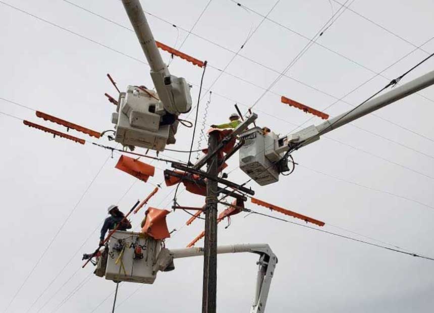 employees in bucket trucks working on line